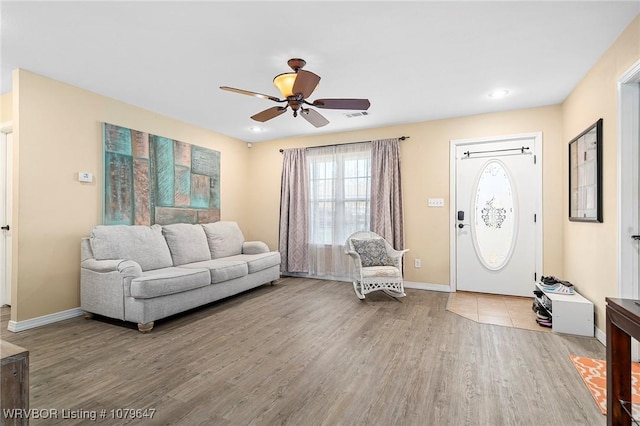 living area featuring visible vents, baseboards, ceiling fan, and wood finished floors