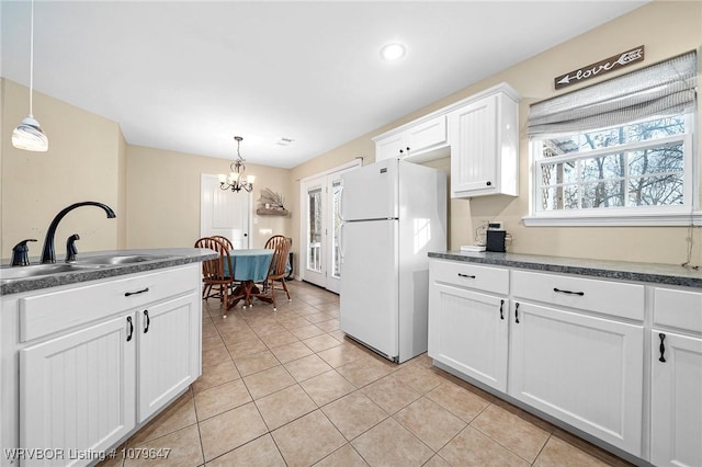 kitchen featuring a chandelier, dark countertops, freestanding refrigerator, and a sink