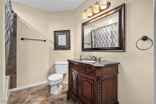 full bath with vanity, baseboards, stone finish flooring, curtained shower, and toilet