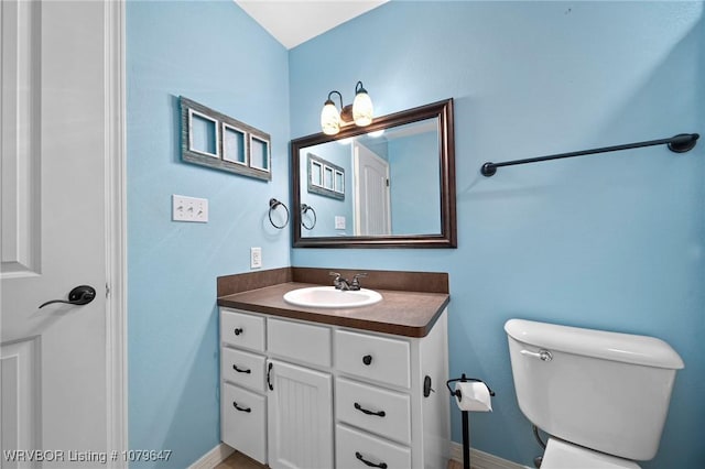 half bath with vanity, toilet, and baseboards
