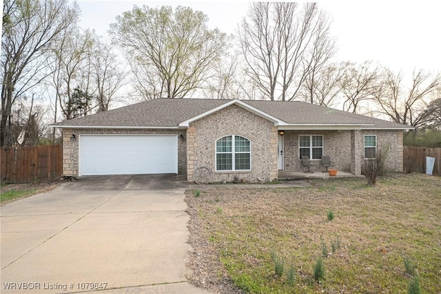 single story home with fence, concrete driveway, a front yard, an attached garage, and brick siding