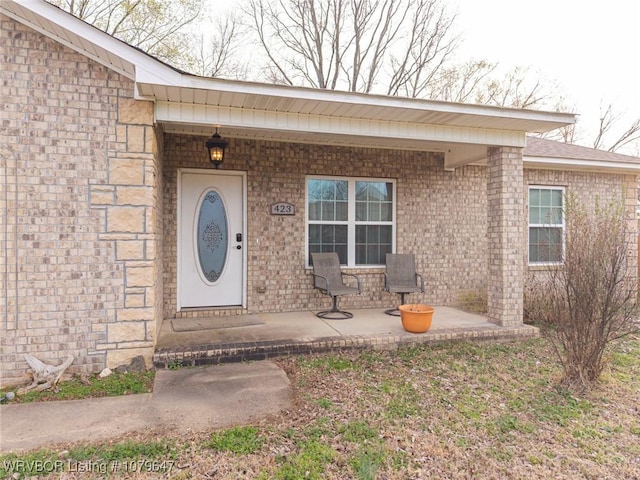 property entrance featuring brick siding and covered porch