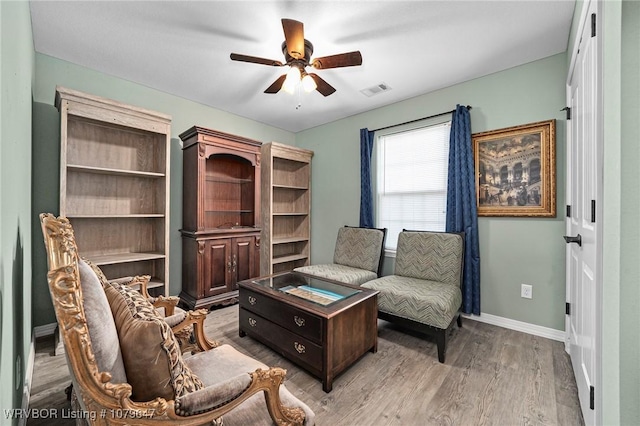 living area with visible vents, baseboards, a ceiling fan, and wood finished floors