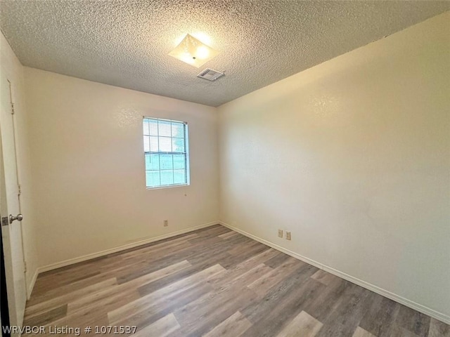 unfurnished room featuring hardwood / wood-style floors and a textured ceiling