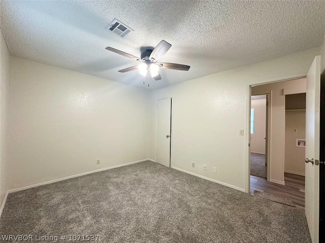 carpeted empty room featuring ceiling fan and a textured ceiling