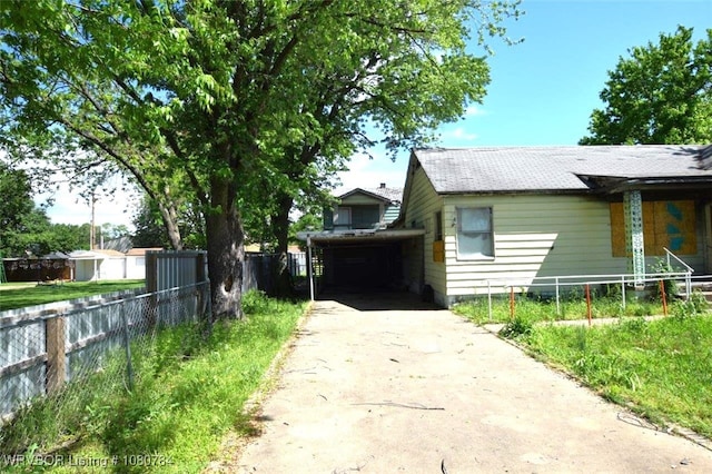 view of side of home featuring fence, concrete driveway, and roof with shingles