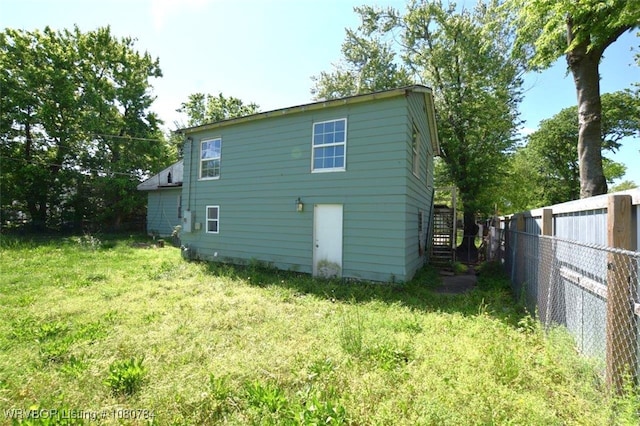 rear view of house with a fenced backyard and a yard