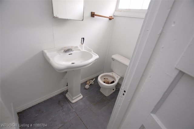half bath with baseboards and toilet