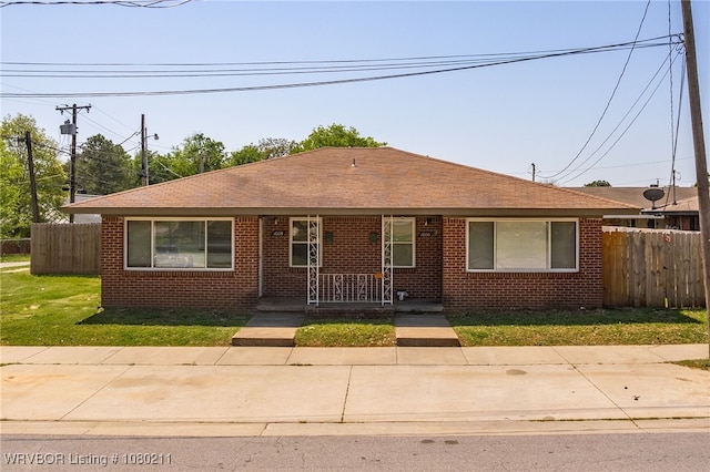 view of front facade featuring brick siding, a porch, and fence