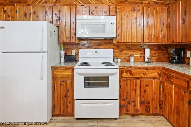 kitchen with brown cabinetry, white appliances, light countertops, and light wood-style floors