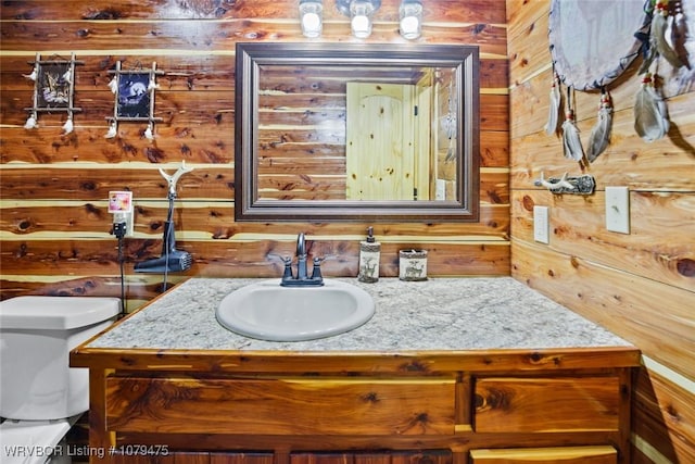 bathroom featuring wooden walls, toilet, and vanity