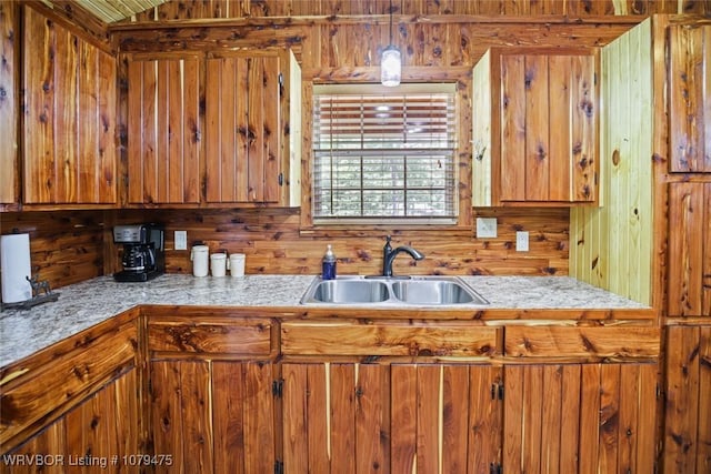 kitchen featuring light countertops, decorative light fixtures, brown cabinets, and a sink