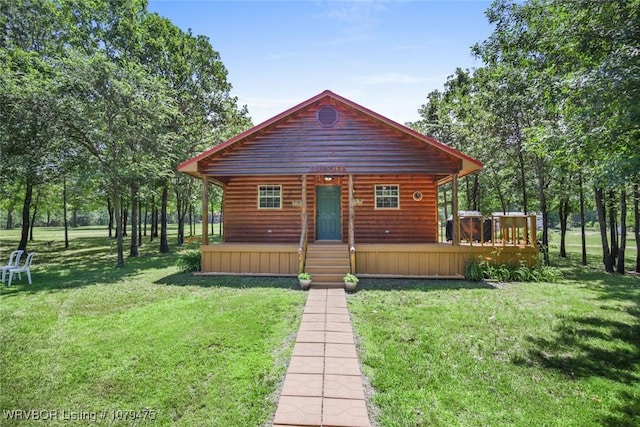 chalet / cabin with log veneer siding, a front lawn, and a wooden deck