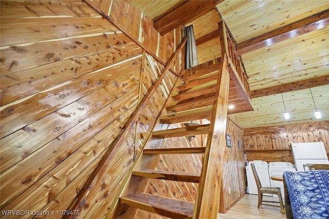 staircase featuring wooden walls, washer and dryer, wood ceiling, and wood finished floors