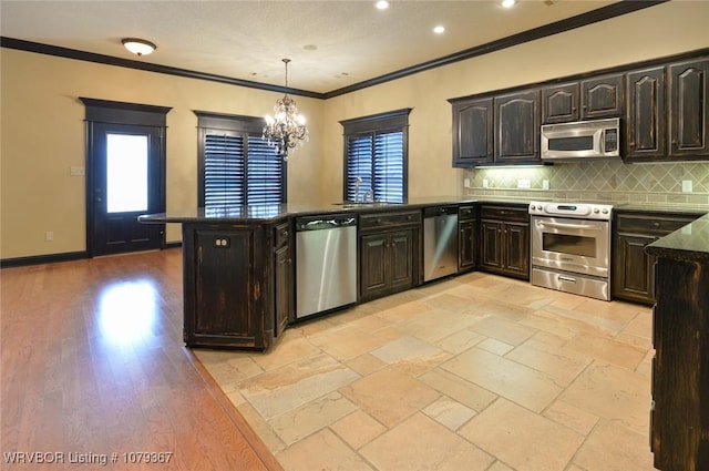 kitchen with baseboards, decorative backsplash, a peninsula, stainless steel appliances, and crown molding