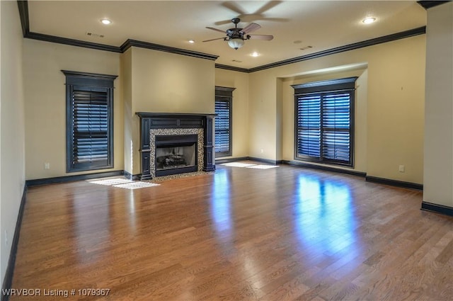 unfurnished living room featuring a ceiling fan, baseboards, wood finished floors, and a high end fireplace