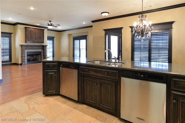 kitchen with dark brown cabinetry, a fireplace, a sink, and stainless steel dishwasher