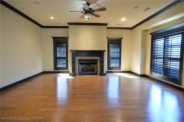 unfurnished living room featuring crown molding, a high end fireplace, ceiling fan, wood finished floors, and baseboards