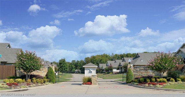 view of street featuring street lighting, a gate, a gated entry, a residential view, and curbs