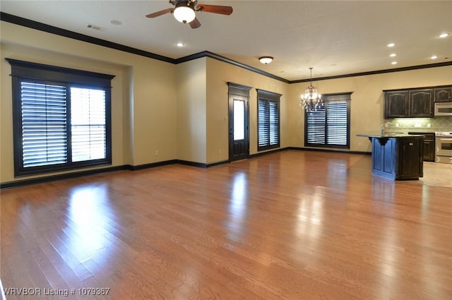 unfurnished living room featuring visible vents, ornamental molding, wood finished floors, baseboards, and ceiling fan with notable chandelier