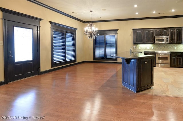 kitchen featuring a notable chandelier, stainless steel appliances, a sink, light wood-type flooring, and decorative backsplash