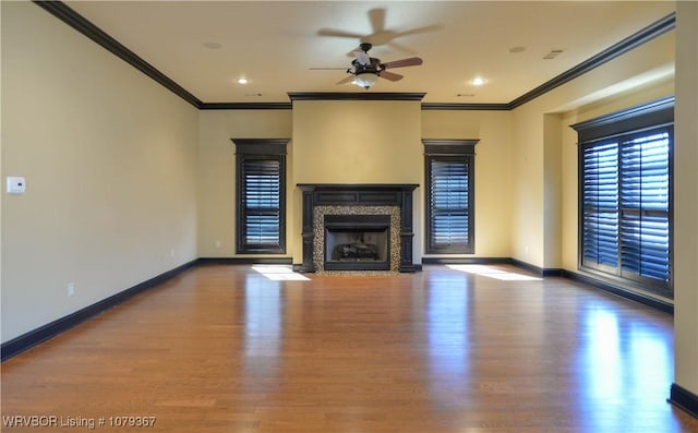 unfurnished living room with wood finished floors, crown molding, baseboards, and a premium fireplace