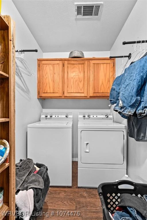 clothes washing area featuring washer and dryer, cabinets, and dark wood-type flooring