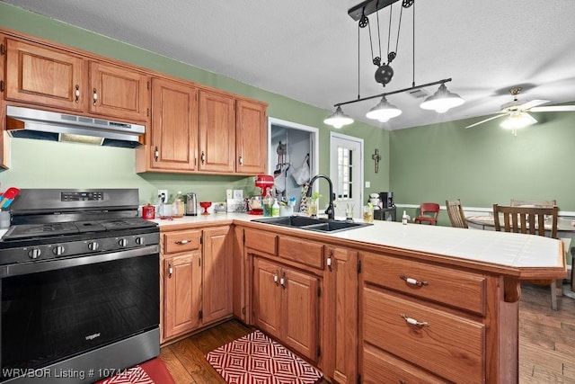 kitchen with pendant lighting, sink, hardwood / wood-style flooring, a textured ceiling, and stainless steel range oven