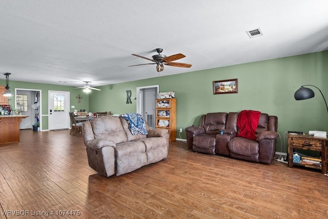 living room with hardwood / wood-style floors, a textured ceiling, and ceiling fan