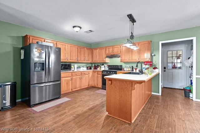 kitchen featuring black electric range oven, sink, stainless steel refrigerator with ice dispenser, hardwood / wood-style flooring, and decorative light fixtures