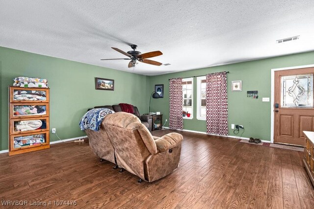 living room featuring ceiling fan, dark hardwood / wood-style floors, and a textured ceiling