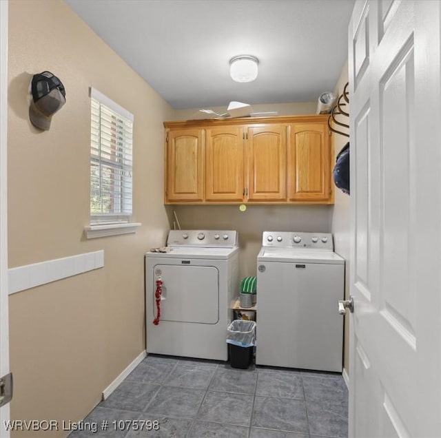 laundry area featuring separate washer and dryer, dark tile patterned floors, and cabinets