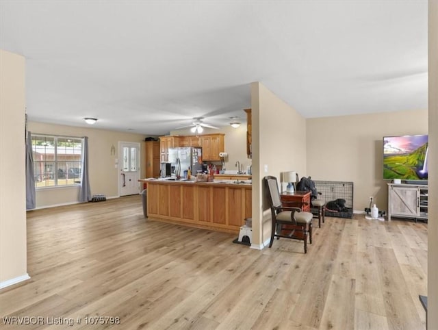 kitchen featuring ceiling fan, stainless steel fridge, kitchen peninsula, and light hardwood / wood-style flooring