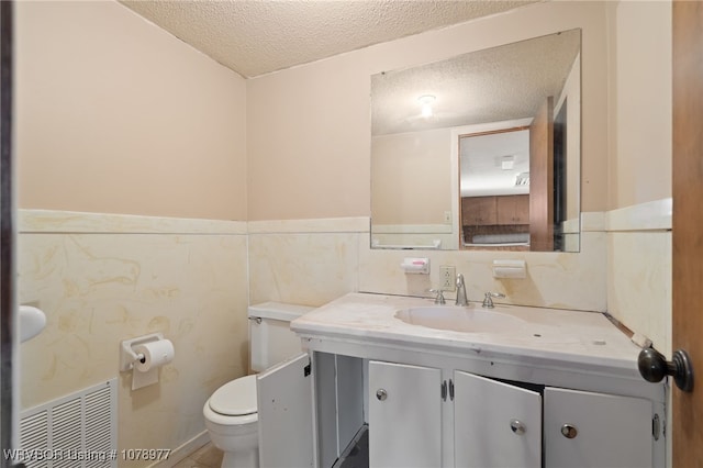 bathroom featuring a textured ceiling, toilet, and vanity