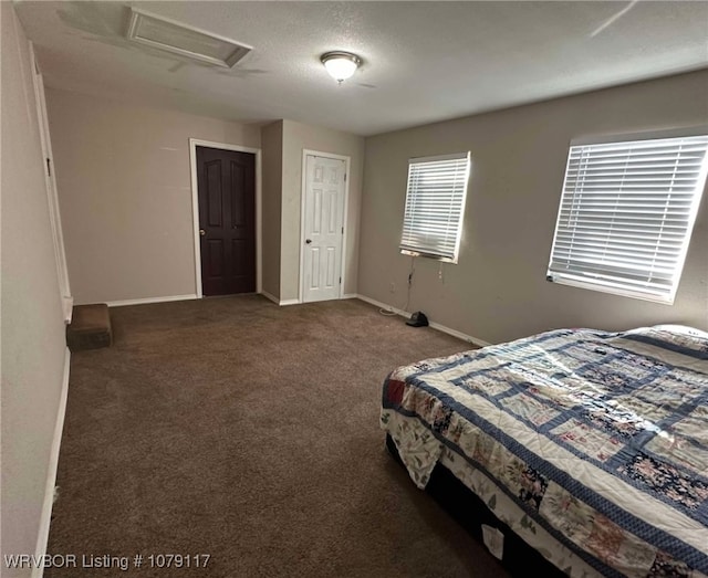 bedroom featuring attic access, dark carpet, and baseboards