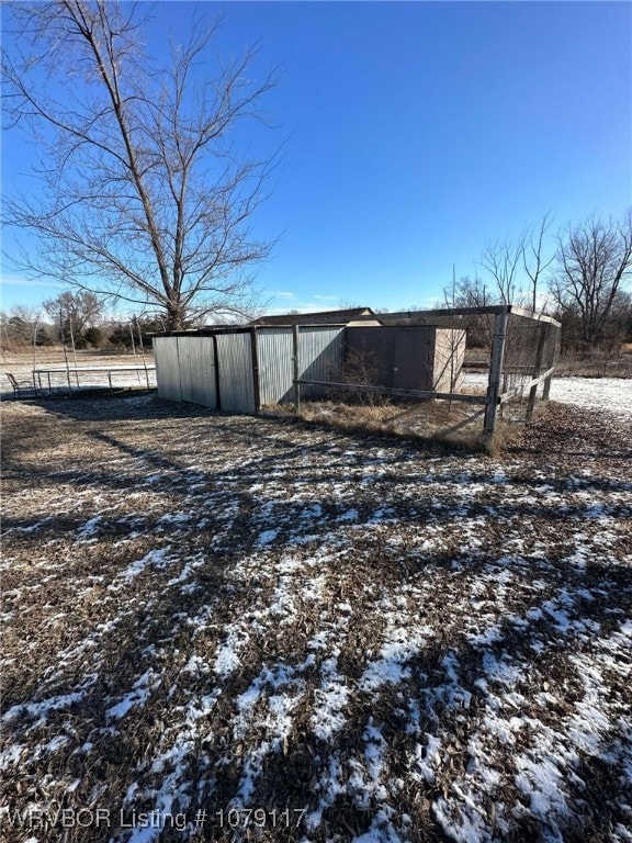 yard covered in snow with an outbuilding and fence