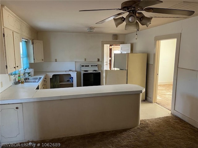 kitchen featuring kitchen peninsula, white appliances, light colored carpet, and white cabinetry