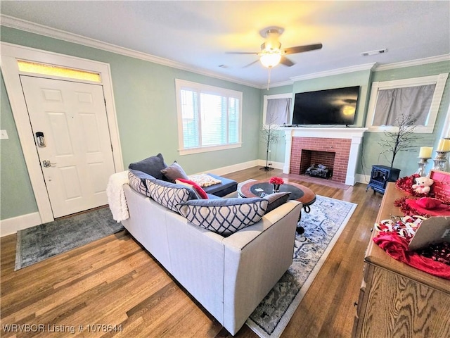 living room with ceiling fan, ornamental molding, a fireplace, and wood-type flooring