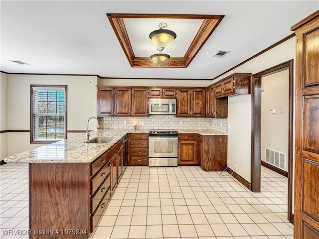 kitchen with a peninsula, appliances with stainless steel finishes, a sink, and visible vents