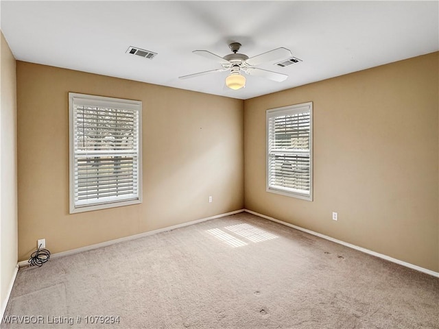 carpeted spare room with ceiling fan, visible vents, and baseboards