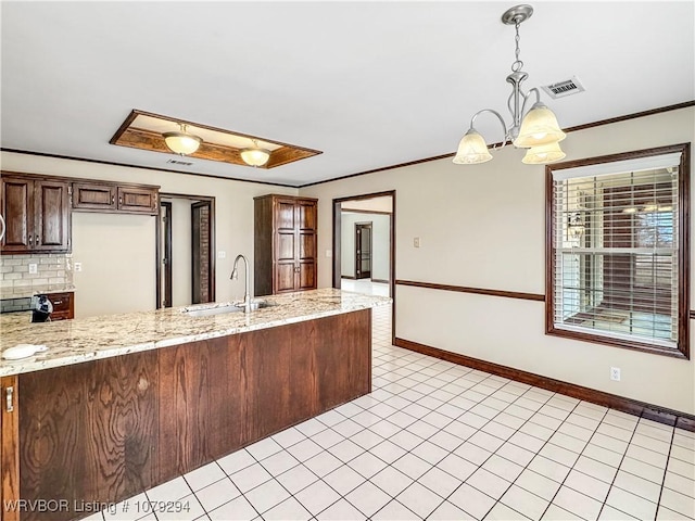 kitchen with crown molding, visible vents, a sink, and backsplash