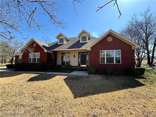 new england style home featuring a front lawn and brick siding