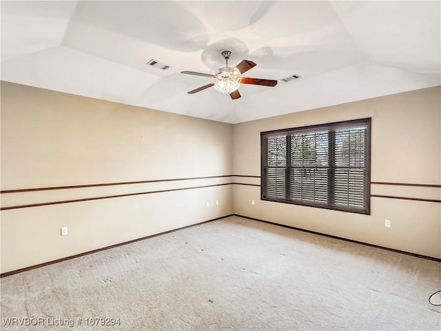 carpeted empty room with lofted ceiling, baseboards, visible vents, and a ceiling fan