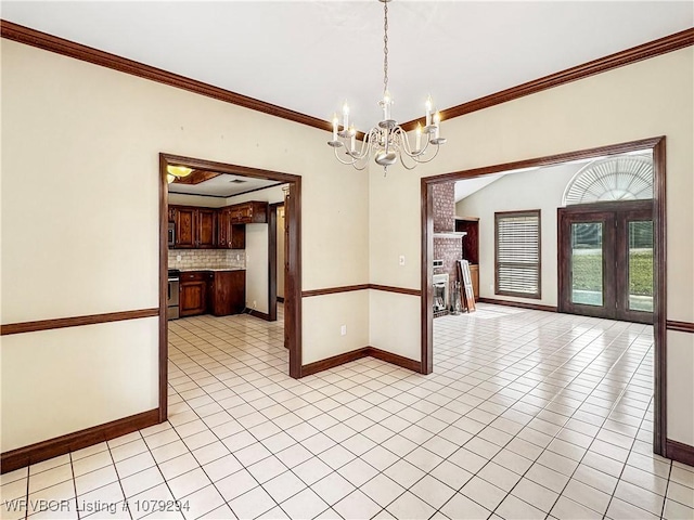 unfurnished dining area featuring light tile patterned floors, a fireplace, baseboards, an inviting chandelier, and crown molding