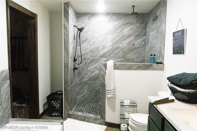 bathroom with a tile shower, vanity, and toilet