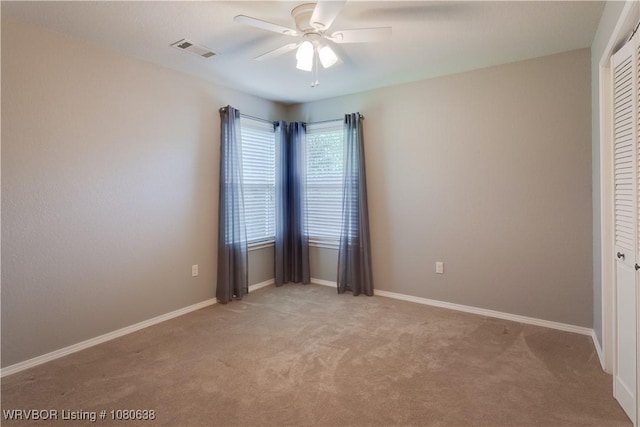 empty room featuring a ceiling fan, baseboards, visible vents, and light carpet