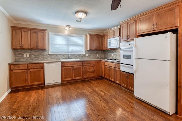 kitchen featuring brown cabinets, a sink, white appliances, visible vents, and a warming drawer