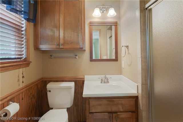 full bath featuring a wainscoted wall, a shower with shower door, vanity, and toilet