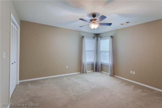 unfurnished room featuring baseboards, ceiling fan, light colored carpet, and visible vents