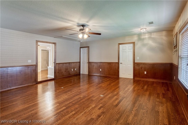 spare room featuring a ceiling fan, a wealth of natural light, wood finished floors, and a wainscoted wall